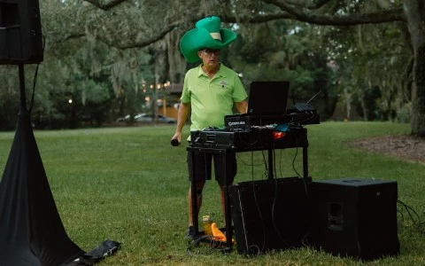 a man wearing a green hat and a microphone standing in a grass field