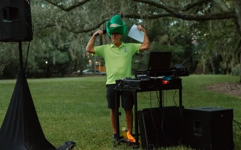 a man in a green hat holding a microphone and standing in a grass field
