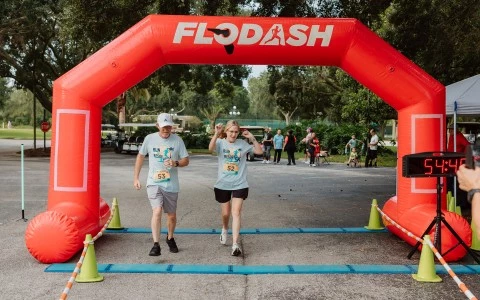 a couple of people running under an inflatable arch