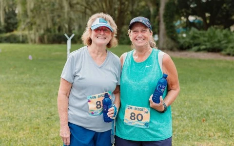 two women standing together with water bottles