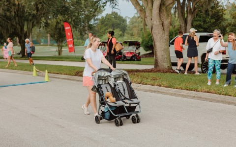 a woman pushing a stroller with two baby strollers