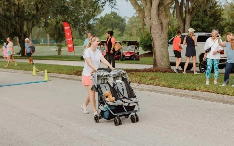 a woman pushing a stroller with two baby strollers