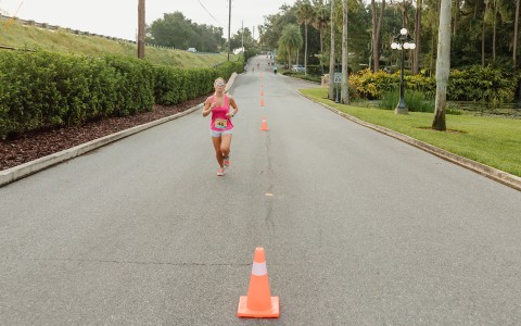 a woman running on a road with orange cones
