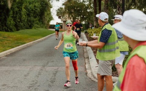 a woman running on a road with a man and a woman in a green vest