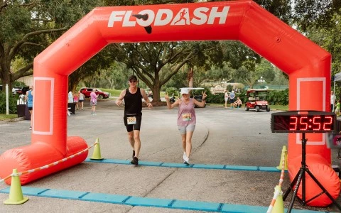 a couple of people running under an inflatable arch