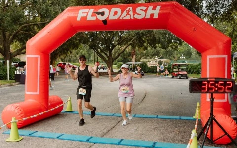 a man and woman running under an inflatable arch