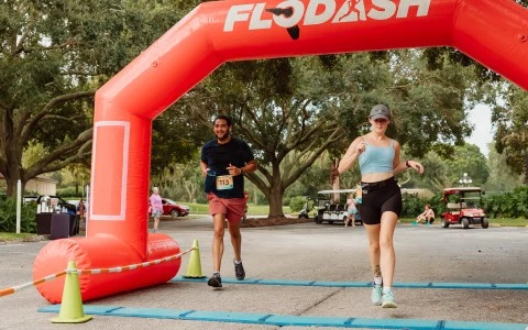 a man and woman running under an inflatable arch