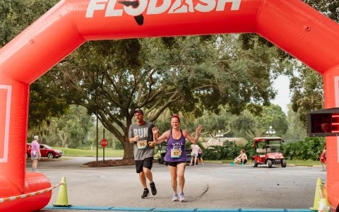 a man and woman running under an inflatable arch