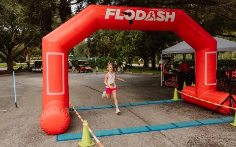 a girl running under an inflatable arch