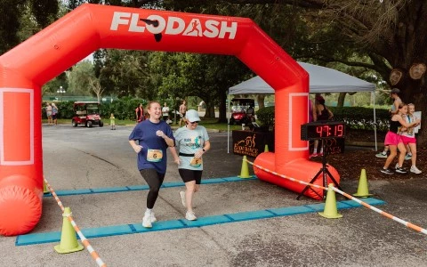 two women running under an inflatable arch