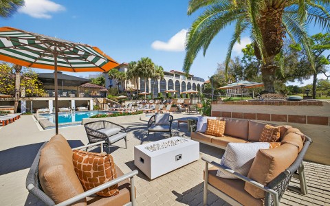 a patio with chairs and umbrellas and a pool