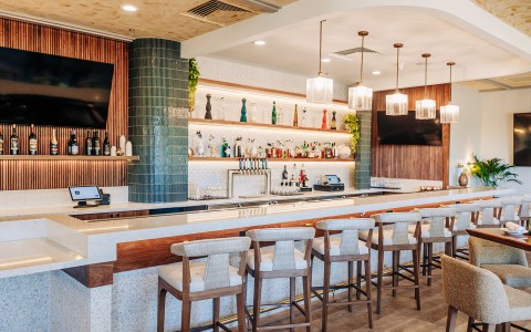a bar with a row of chairs and a tv