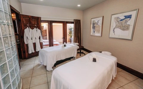a massage room with white beds and towels