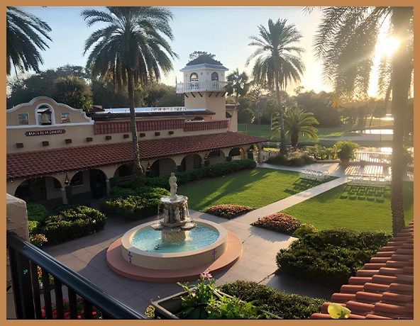 a fountain in a courtyard with a building and palm trees