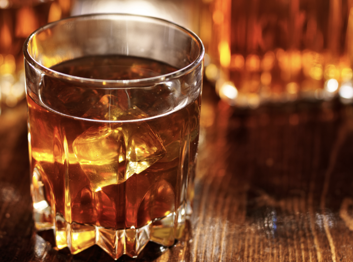 a glass of amber liquid with ice