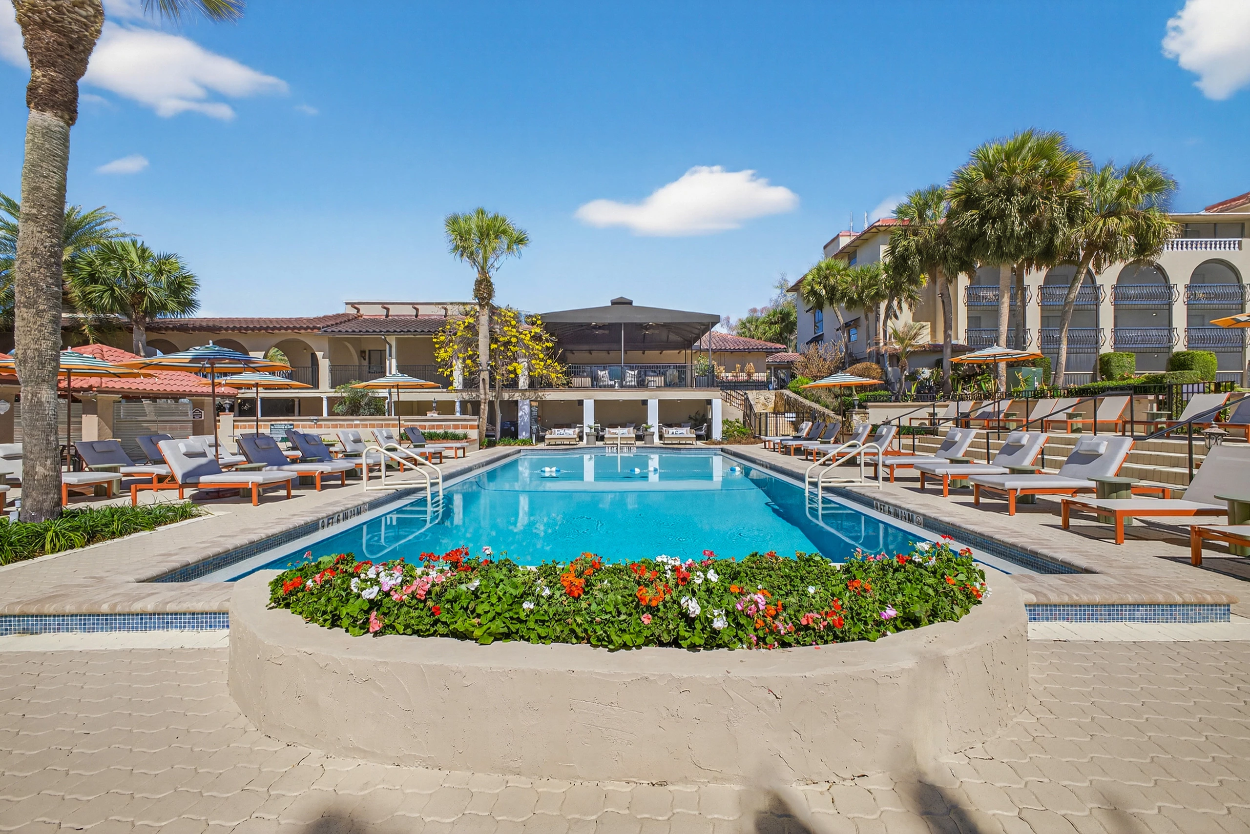 a pool with chairs and umbrellas in front of a building