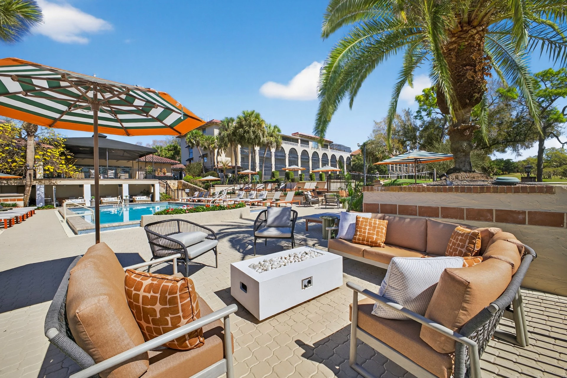 a patio with chairs and umbrellas and a pool