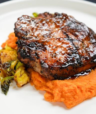 a piece of meat with mashed potatoes and vegetables on a white plate