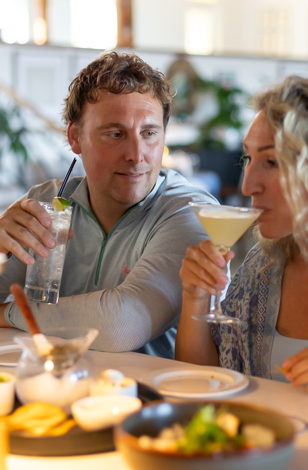 a man and woman drinking cocktails at a table