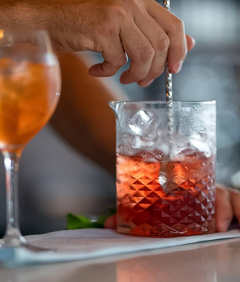 a person's hand mixing a drink with a straw