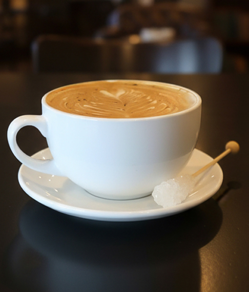 a cup of coffee with a spoon and sugar on a plate