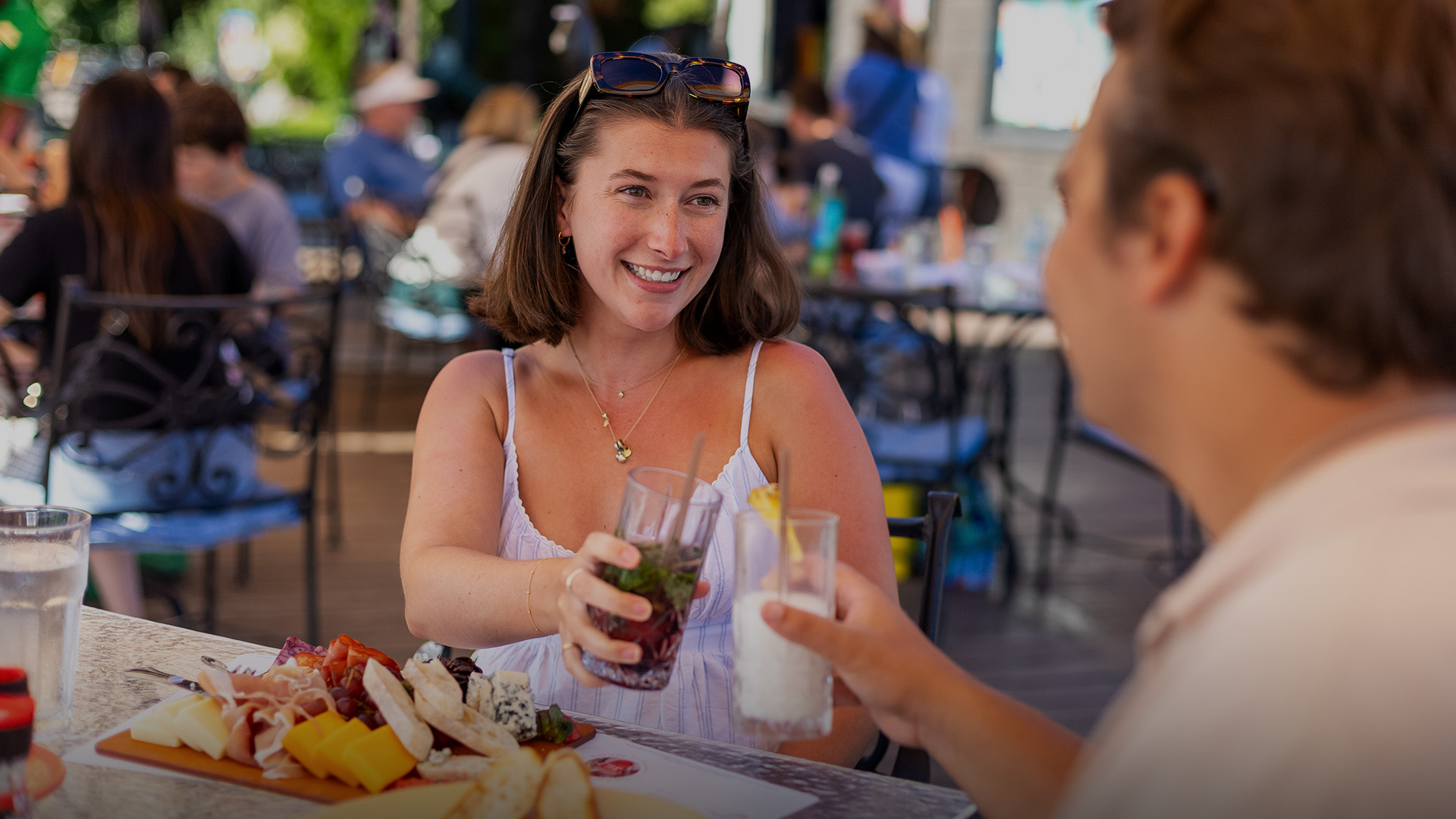 a woman holding drinks and smiling at another woman