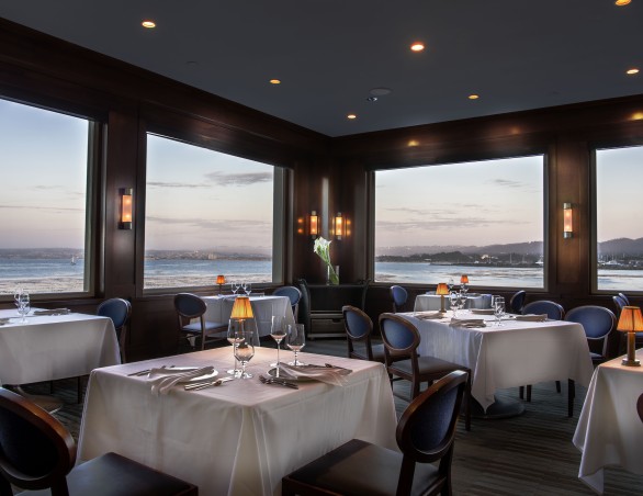 a room with tables and chairs and a view of the ocean
