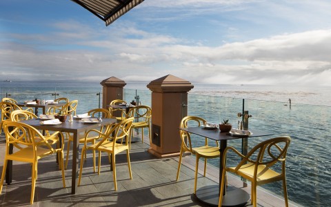 a table and chairs on a patio overlooking a body of water
