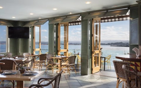a room with tables and chairs and a view of the water