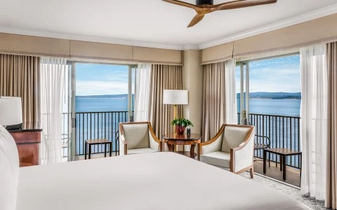 a room with a bed and chairs and a table with a fan