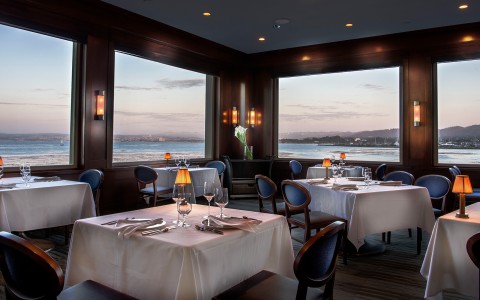 a restaurant with tables and chairs and a view of the ocean