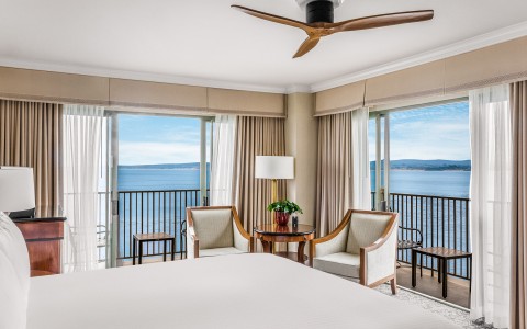 a room with a bed and chairs and a table with a fan