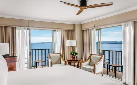 a room with a bed and chairs and a table with a fan