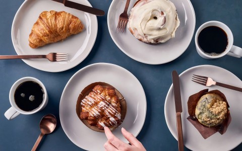 a plate of pastries and a hand touching a piece of pastry