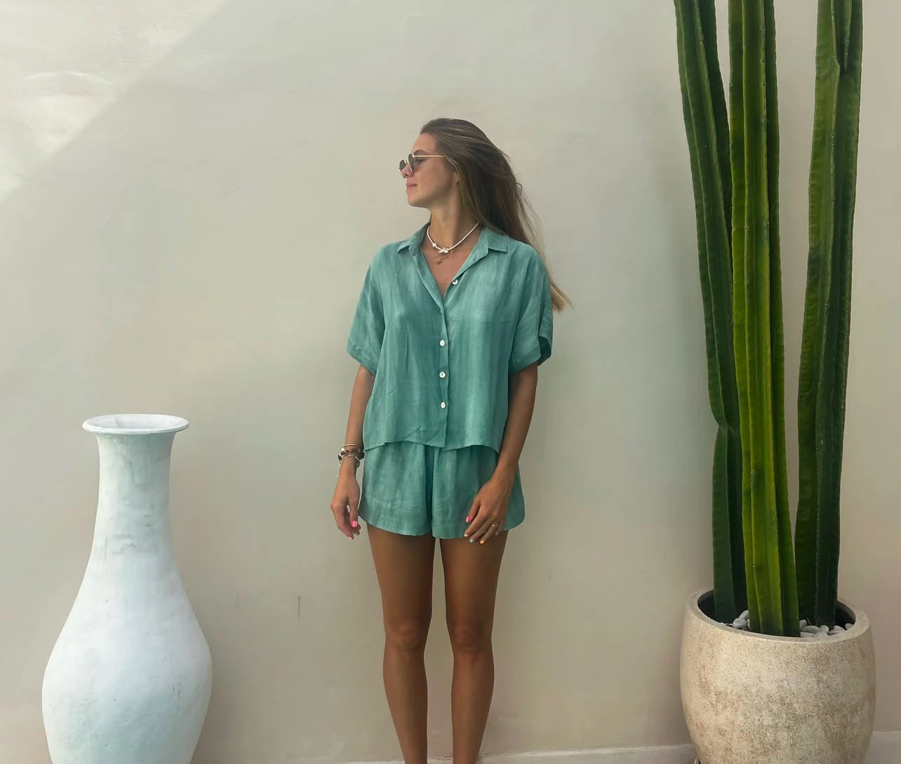 a woman standing in front of a wall with a cactus