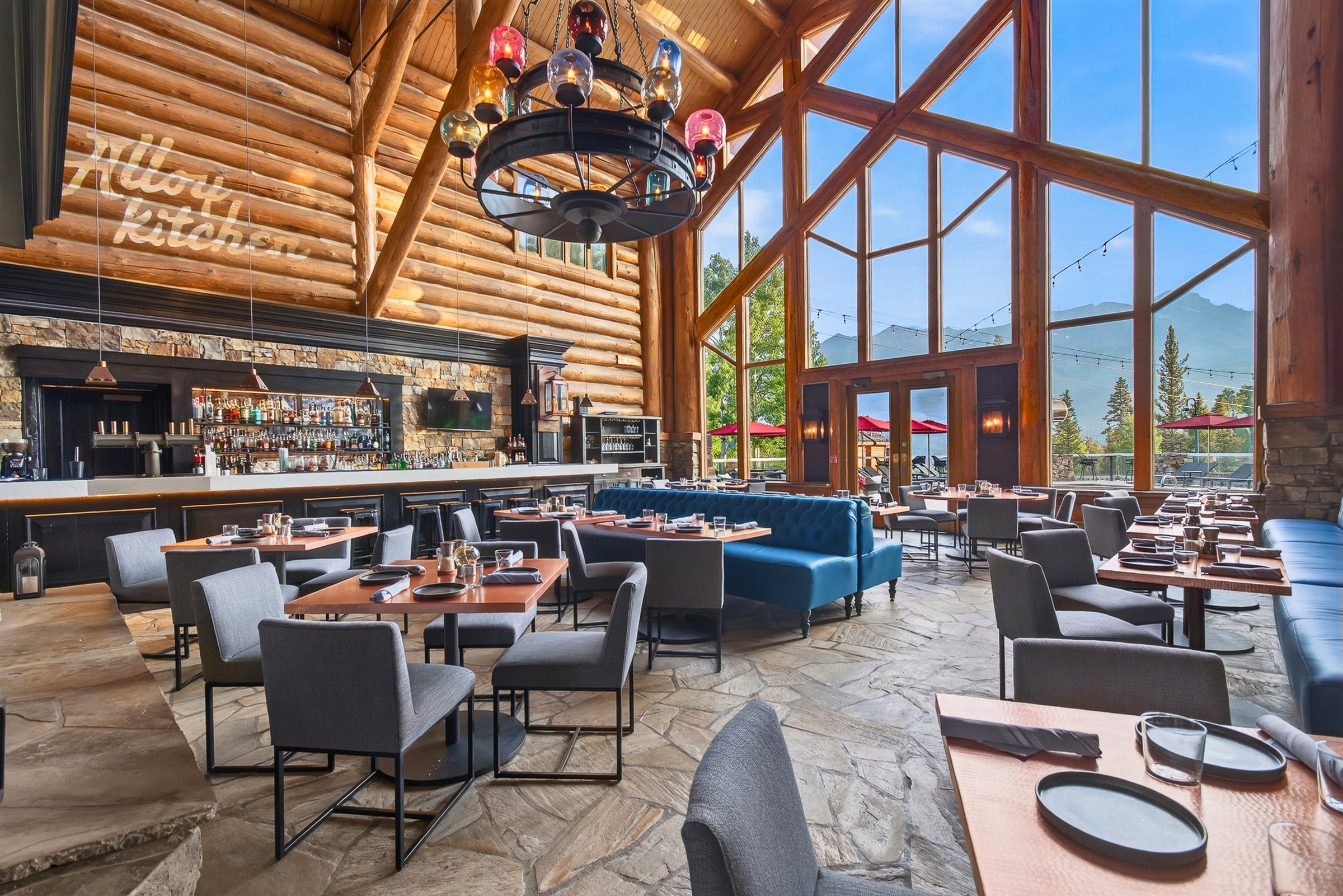 The remodeled dining room at Alloy Kitchen, with blue tufted banquettes, copper tables and floor-to-ceiling mountain views