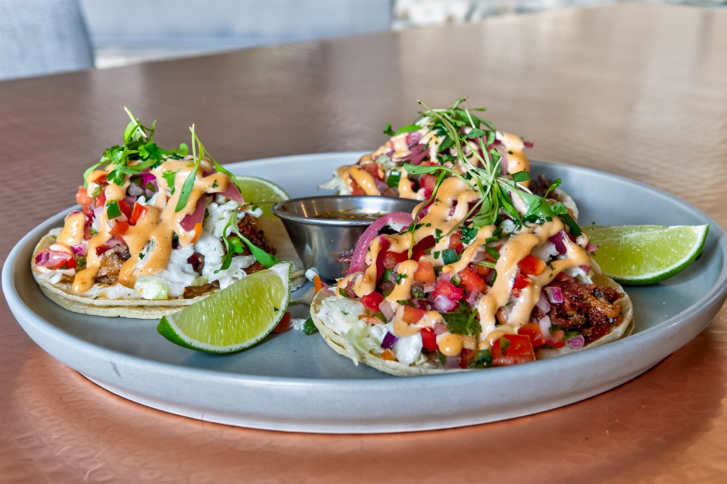 a plate of tacos with sauce and limes