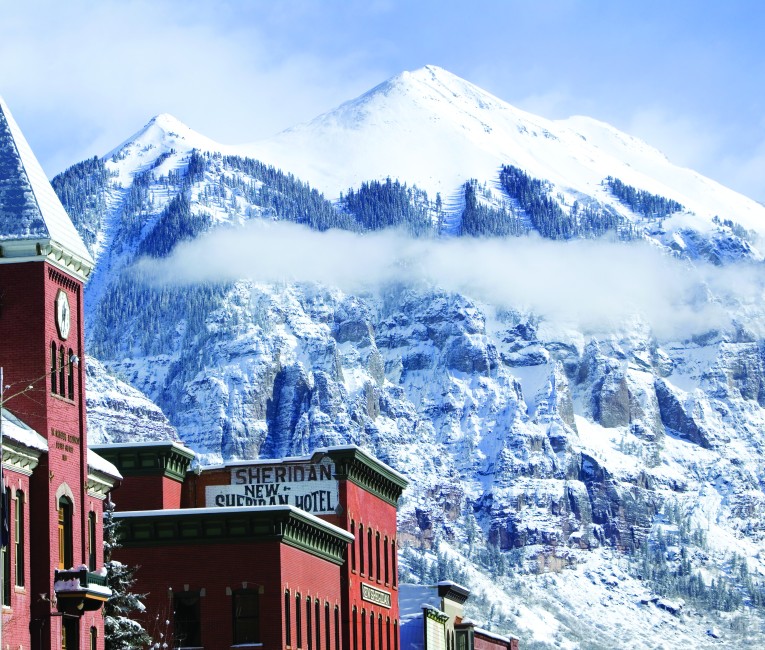 a building with a clock on it and a snowy mountain in the background