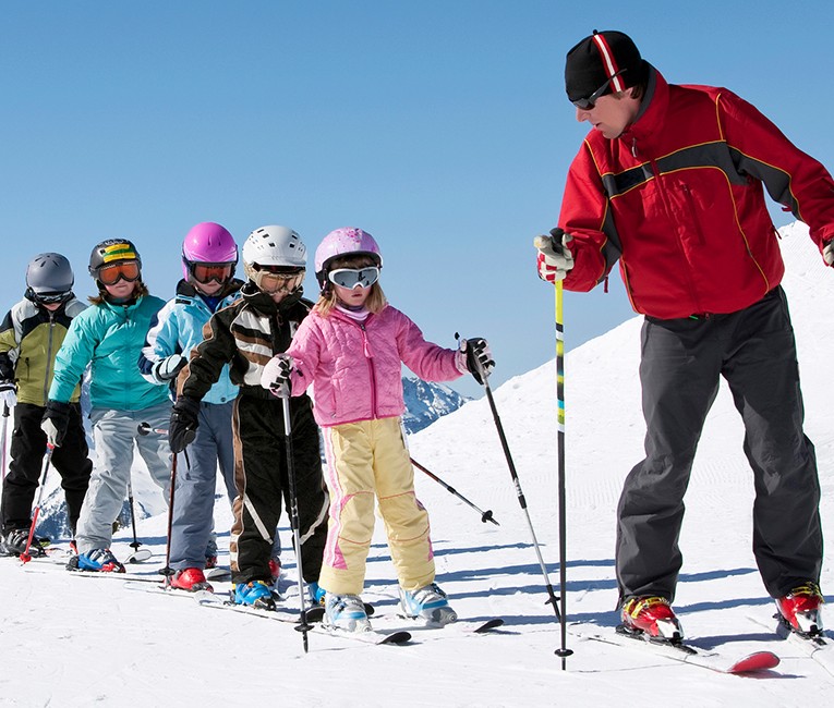a ski instructor teaching young kids how to ski on the slopes