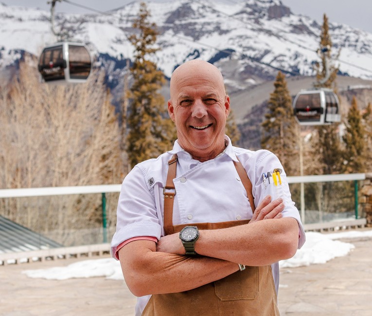 a man wearing an apron and standing with his arms crossed