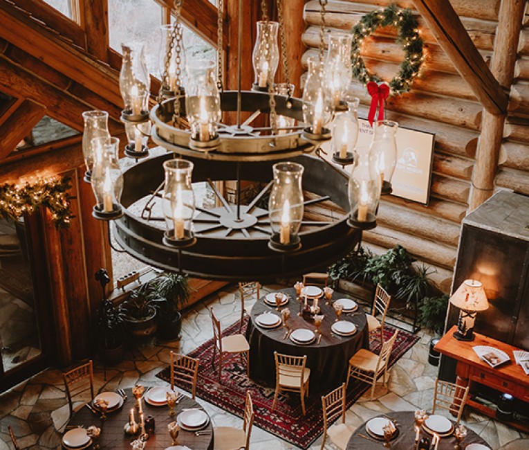 a chandelier with a round table and chairs in a log cabin