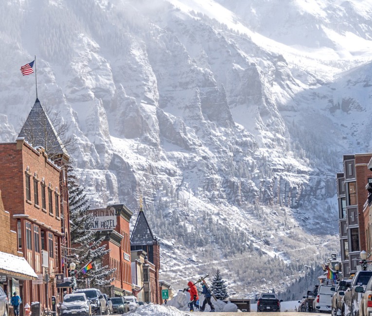 a snow covered mountain with buildings and people walking on a street