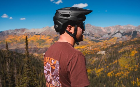 a man wearing a helmet and sunglasses looking at mountains