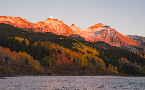 a mountain range with trees and a body of water