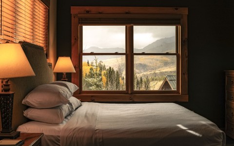 a bed with pillows and a lamp in front of a window