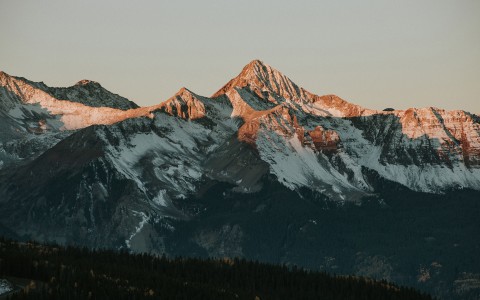 a snowy mountain tops with trees in the background