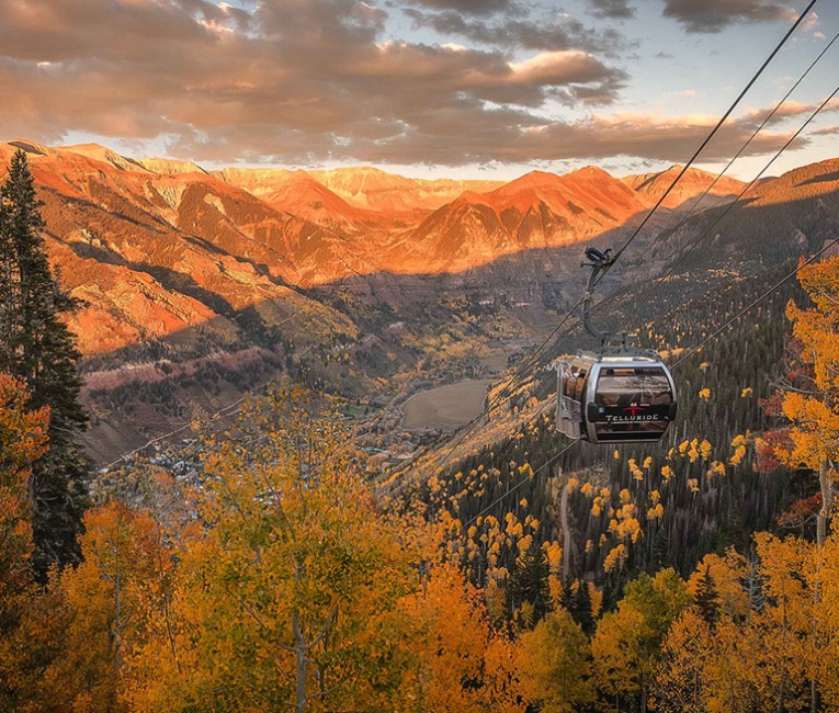 a cable car over a valley with mountains and trees
