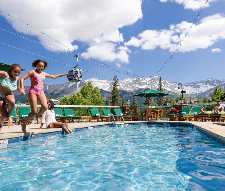 a group of kids jumping into a pool