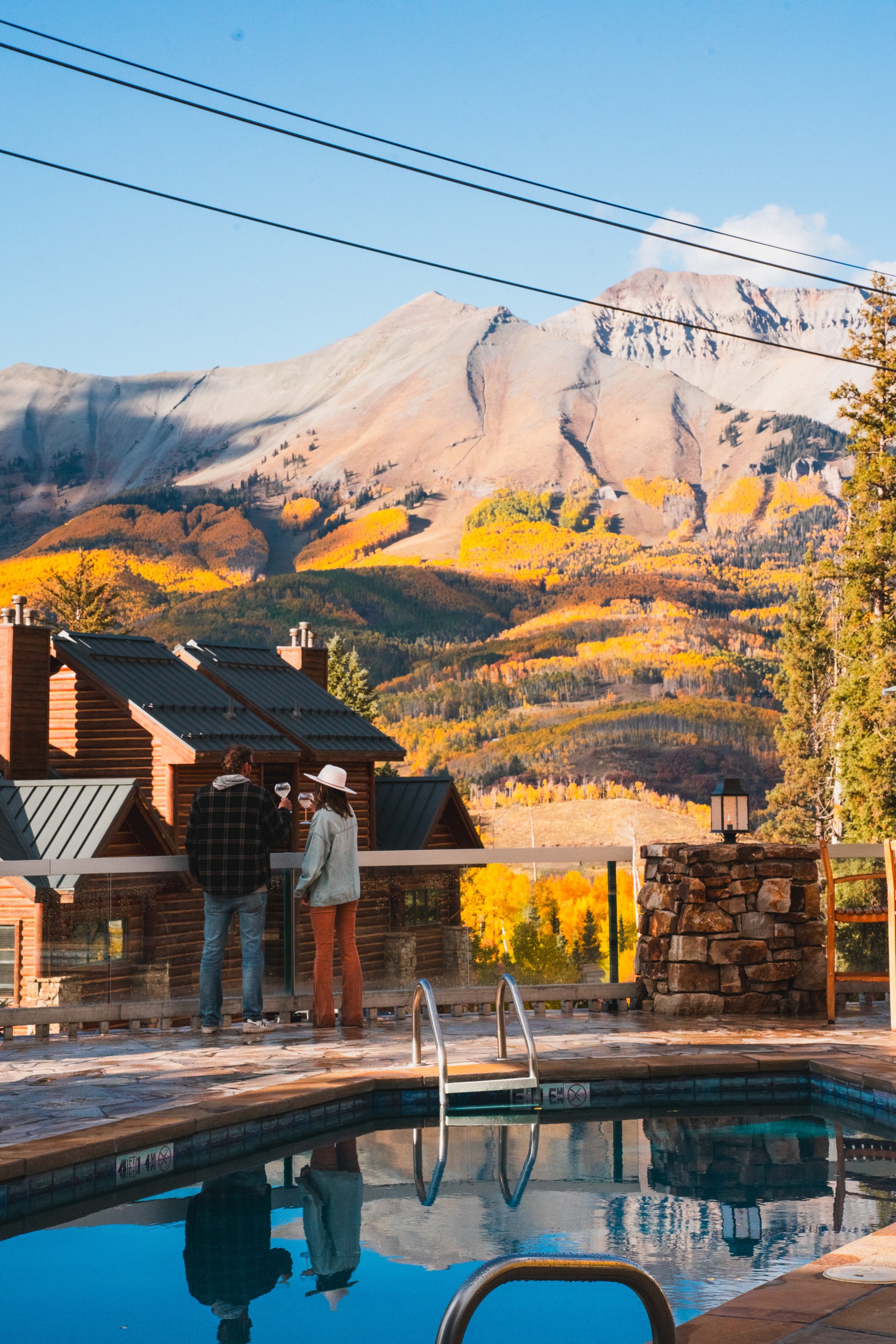 a group of people standing by a pool with mountains in the background