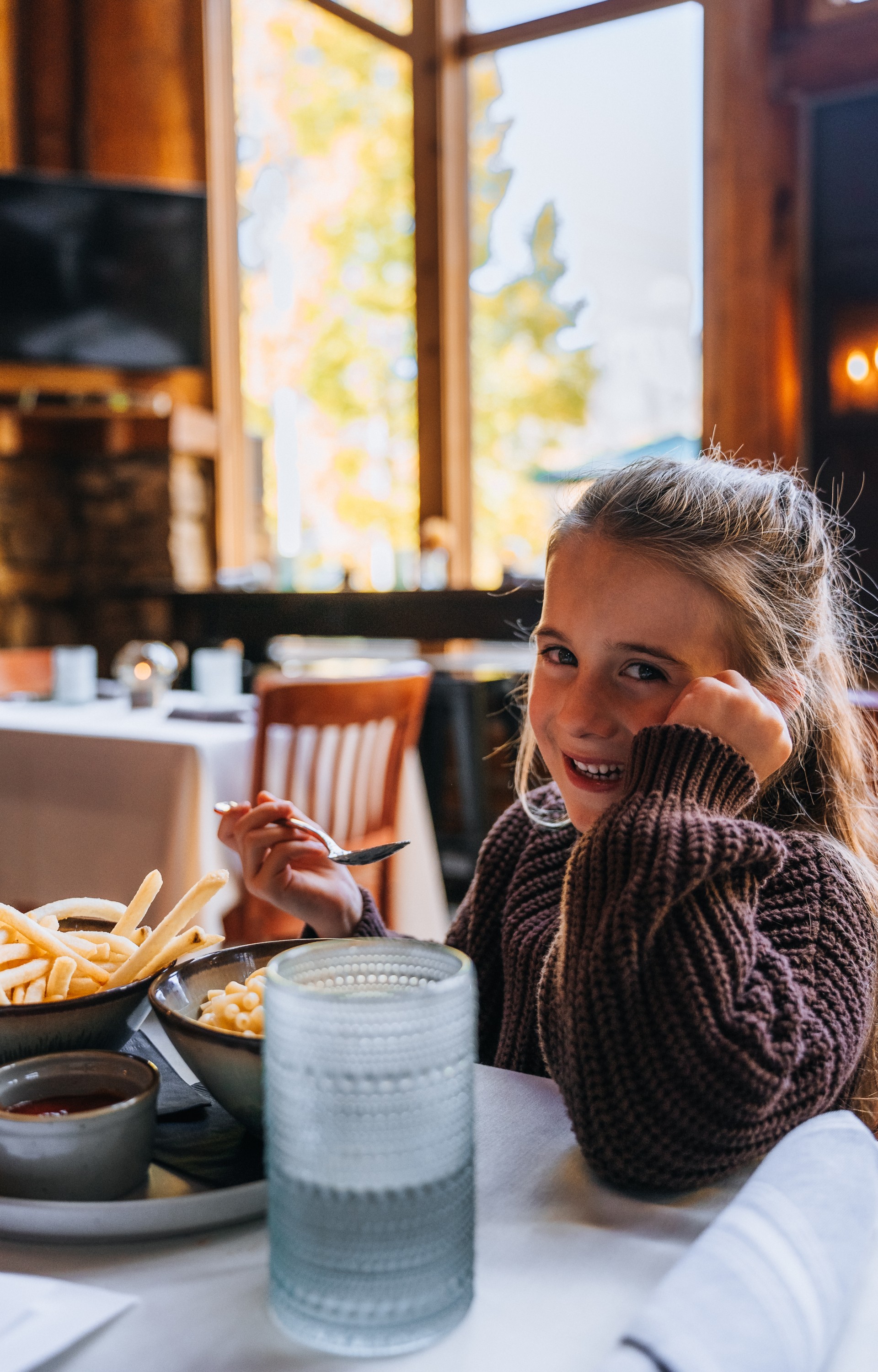 a girl sitting at a table with a bowl of food